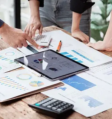 Business professionals collaborating over financial reports, data charts, calculator and tablet in modern office